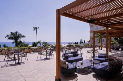 a patio with chairs and tables and a pergola at Atlantica Bay - Adults Only in Limassol