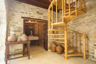 a wooden spiral staircase in a room with vases at Whitestone Mill in Pano Lefkara