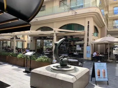 a statue in front of a building with people sitting at tables at Central Large 2BD APT near the Beach in Larnaka