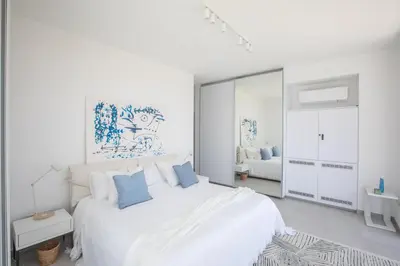 a white bedroom with a large white bed with blue pillows at Villa Olivine Pearl 3 in Protaras