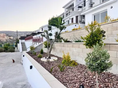 a garden in front of a building with trees at Pissouri Image in Pissouri