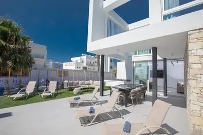 a patio with chairs and a table on a building at Kube Luxury Villas in Ayia Napa