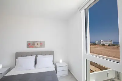 a bedroom with a bed and a large window at Walk to Protaras Center & Beach- Your Dream Escape, Blue Island Villa in Protaras