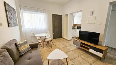 a living room with a couch and a tv and a table at FlipFlop City Center Apartment in Larnaka