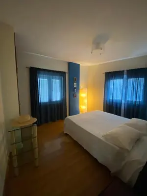 a bedroom with a white bed and two windows at Aphrodite Sea View Apartment in Larnaka