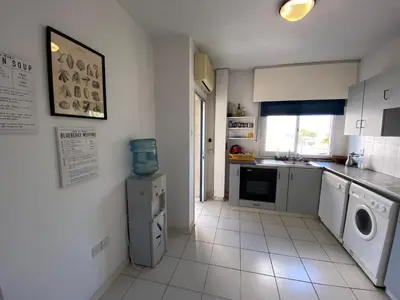 a white kitchen with a washer and dryer in it at private room in a shared flat at best location in Limassol