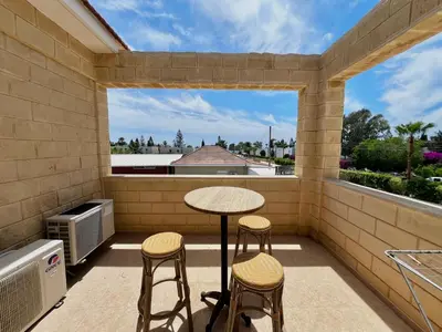 a small balcony with a table and stools and a window at STAY Pernera House in Ayia Napa