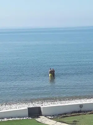 two people sitting on a surfboard in the water at SEAFRONT BEACH PARTY VILLA in Pervolia
