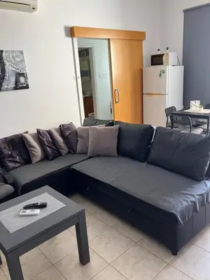 a black couch in a living room with a table at Protaras, Janas apartment in Protaras