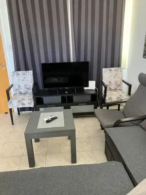 a living room with a tv and two chairs and a table at Protaras, Janas apartment in Protaras