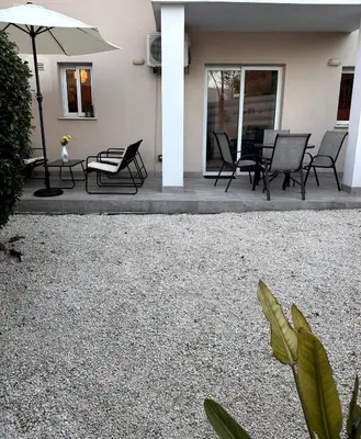a group of chairs and an umbrella on a patio at Olymbos Garden Apartment IV in Ayia Napa
