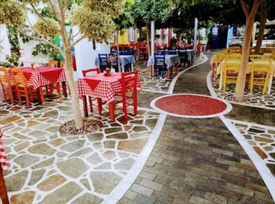 a patio with red tables and chairs and trees at 1 bedroom apartment with a magnificent sea view in Limassol
