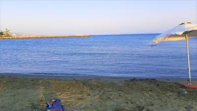 a beach with an umbrella and the ocean at 1 bedroom apartment with a magnificent sea view in Limassol