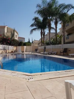 a large swimming pool with palm trees and buildings at Panorama Village Complex in Paralimni