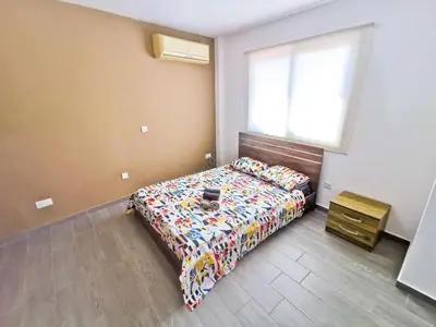 a bedroom with a bed with a comforter and a window at Hidden Gem City Studio in Larnaka