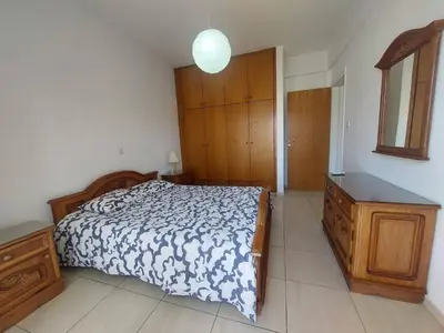 a bedroom with a bed and a wooden dresser at Sunny 2 Bedroom Larnaca Center in Larnaka