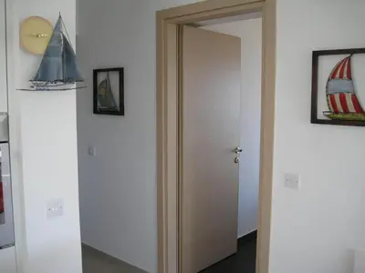 a wooden door in a room with a mirror at Trident Beach Apartment in Protaras