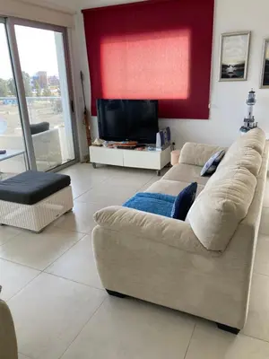 a living room with a couch and a television at Trident Beach Apartment in Protaras