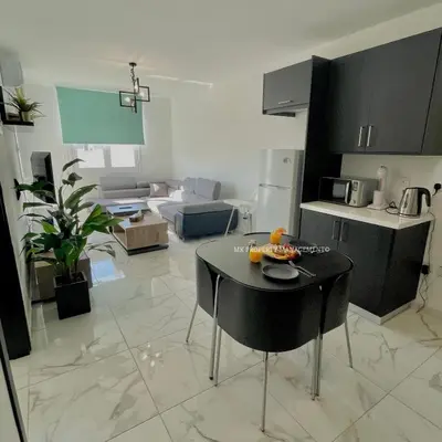 a living room with a table in the middle of a kitchen at Mad beach in Protaras