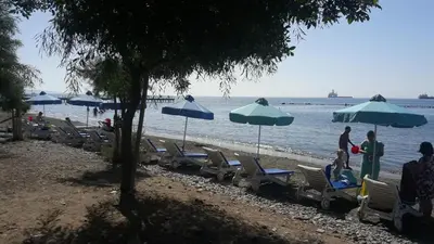 a group of chairs and umbrellas on a beach at Ariadne 1, Sea Side Boutique Apartment in Limassol