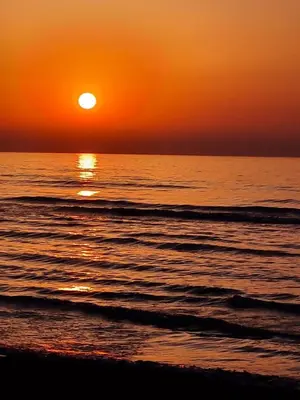 an orange sunset over the ocean with a beach at Alex Beach Apartment 34 in Larnaka