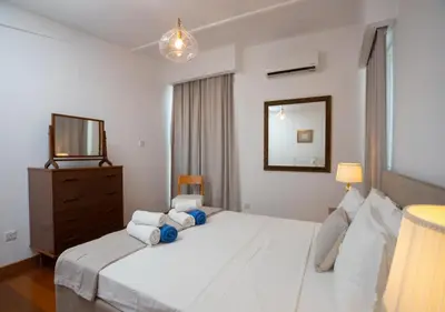 a bedroom with a white bed with a dresser and a mirror at 1-80 Collection Penthouse by TrulyCyprus in Limassol