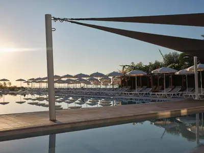 a pool with tables and chairs and umbrellas at Atlantica Sungarden Park in Ayia Napa
