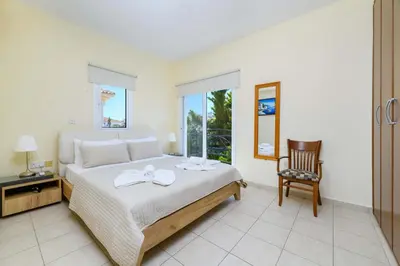 a bedroom with a bed and a chair and a window at Villa Alexander in Protaras