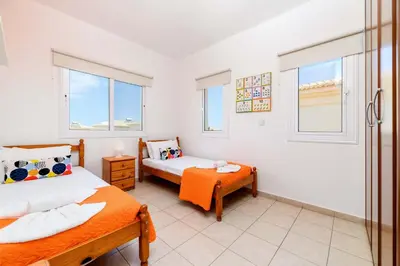 a bedroom with two beds and two windows at Villa Alexander in Protaras