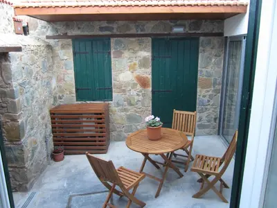 a patio with a table and chairs and green doors at I Plateia in Kalopanayiotis