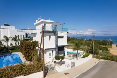 a building with a swimming pool and the ocean at Seaside Luxury Villa with Heated Pool in Paralimni