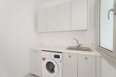 a white kitchen with a washing machine and a sink at Seaside Luxury Villa with Heated Pool in Paralimni