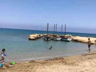 a group of people on a beach with boats in the water at Seaside Luxury Villa with Heated Pool in Paralimni