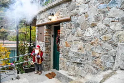 a girl in a santa hat standing outside a stone building at Sophias Cottage in Askas