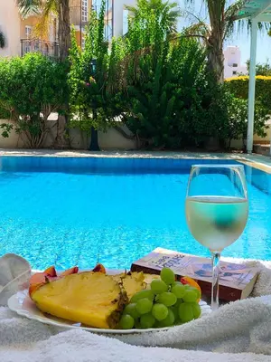 a plate of fruit and a glass of wine next to a pool at Villa Elena in Protaras