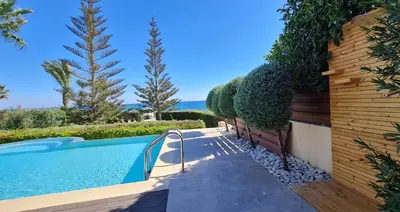 a swimming pool in a yard with trees and bushes at Villa del Mar Heated pool in Mazotos