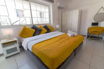 a bedroom with a large bed with a yellow blanket at Jana's 2-BR Apartment in Larnaca in Larnaka