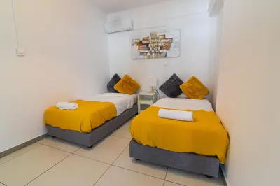 two beds in a room with yellow blankets at Jana's 2-BR Apartment in Larnaca in Larnaka