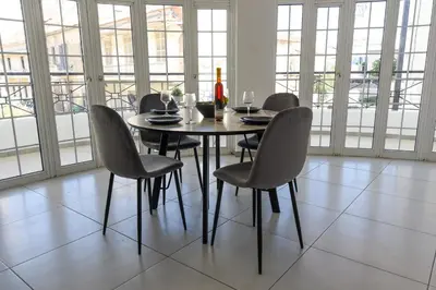 a dining room with a table and chairs and windows at Jana's 2-BR Apartment in Larnaca in Larnaka