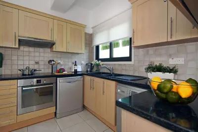 a kitchen with wooden cabinets and a bowl of fruit on the counter at Villa Greko in Protaras