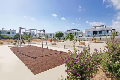 a park with a swing and flowers and buildings at Villa Theresa in Protaras