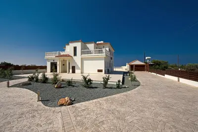 a large white house on a stone driveway at Amani Villa in Protaras
