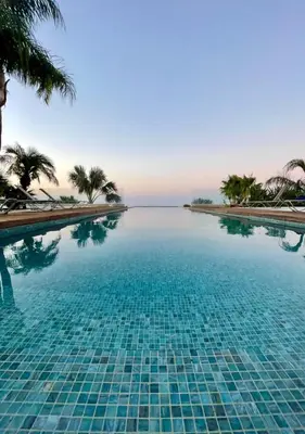 a swimming pool with palm trees and the ocean at Bay View Villa in Protaras