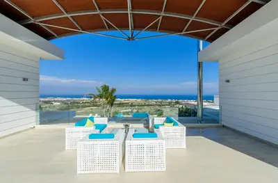 a patio with blue chairs and a view of the ocean at Bay View Villa in Protaras