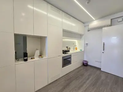 a white kitchen with white cabinets and a wooden floor at City Centre Studio Apartments Nicosia in Nicosia