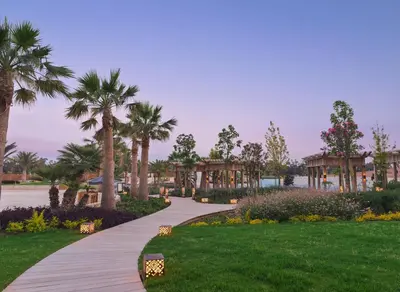 a walkway in a park with palm trees and plants at City of Dreams Mediterranean - Integrated Resort, Casino & Entertainment in Limassol
