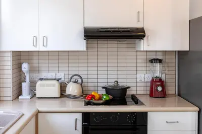 a kitchen with white cabinets and a black stove top oven at Protaras Sapphire Seaside Villa in Protaras
