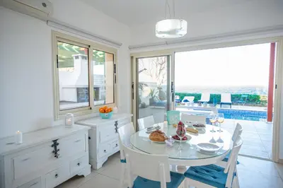 a white dining room with a table and chairs at Protaras Artisan Seafront Villa in Protaras