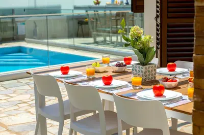 a table and chairs with a table and a pool at Ayia Napa Ionion Seaside Villa in Ayia Napa