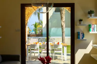 a glass door leading into a dining room with a table and chairs at Ayia Napa Ionion Seaside Villa in Ayia Napa